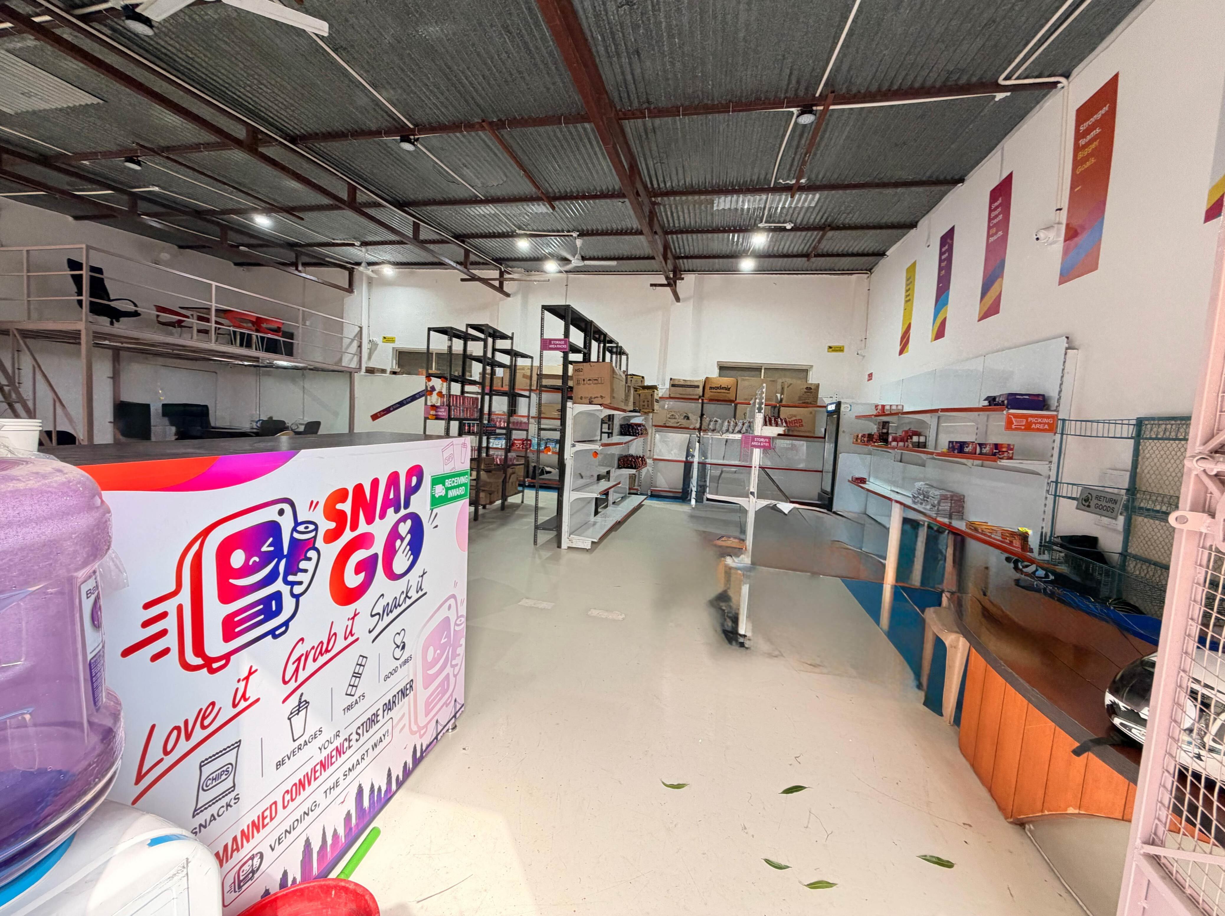SnapGo central warehouse floor in Bhugaon, Pune with storage racks and the SnapGo branded receiving counter